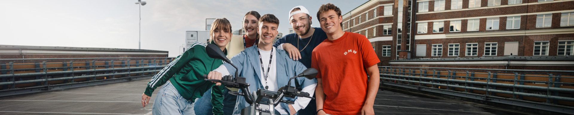 Fünf Azubis stehen um einen BMW CE02 Scooter