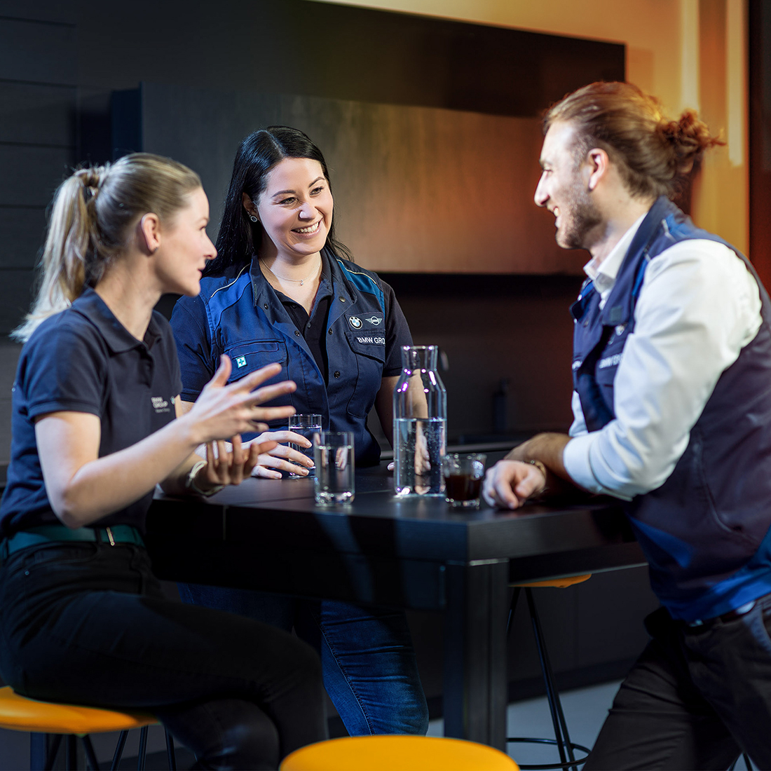 Drei Berufserfahrene bei BMW, zwei Frauen und ein Mann, nehmen an einem Meeting teil.