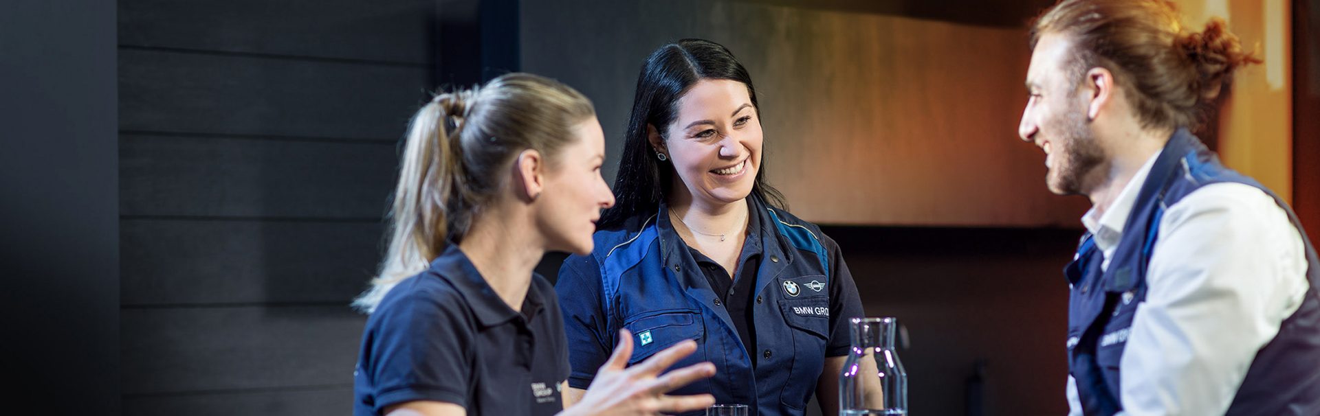 Drei Berufserfahrene bei BMW, zwei Frauen und ein Mann, nehmen an einem Meeting teil.