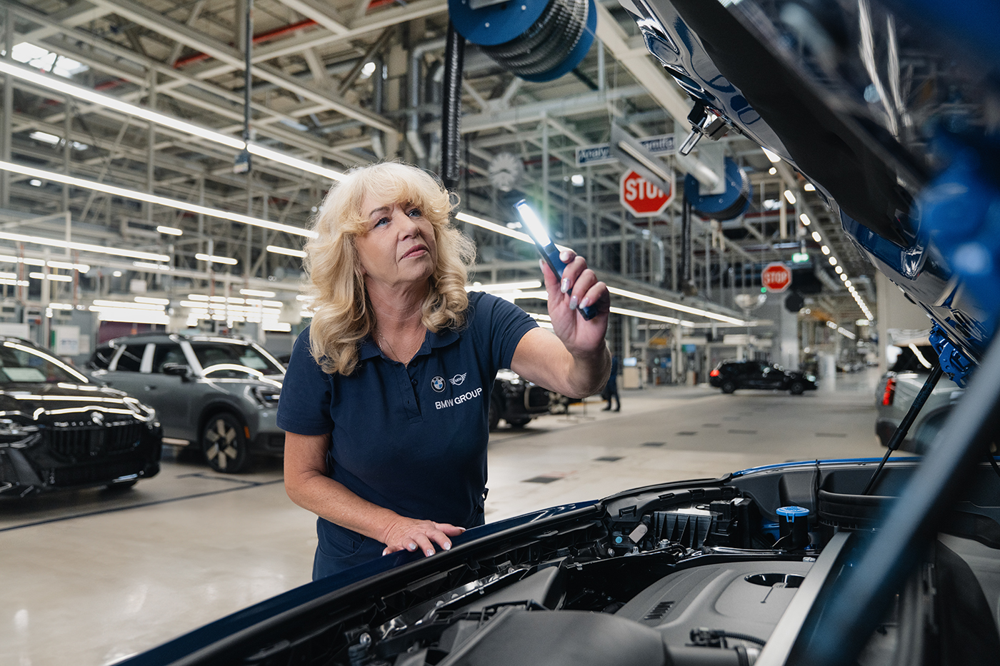 Un collègue expérimenté montre à un apprenti une étape de travail dans l'usine de BMW Group.