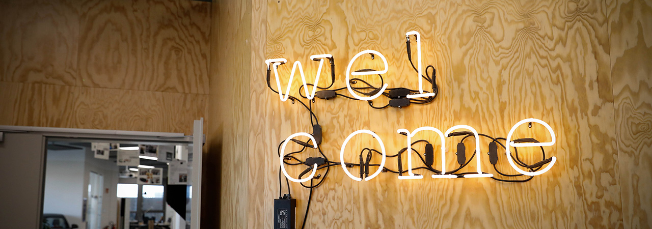 Auf dem Bild ist ein Neonschild mit der Aufschrift „welcome“ im Innovation Lab in München zu sehen.