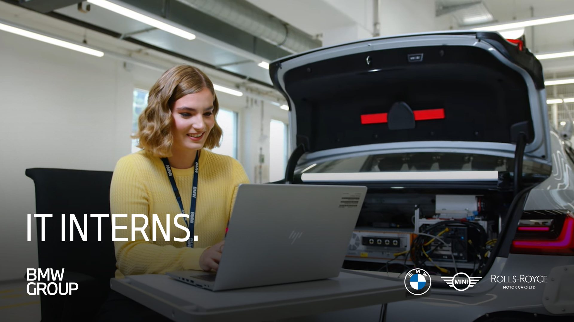 Einblicke in das Praktikum im Bereich IT bei der BMW Group. Eine Praktikantin arbeitet mit dem LapTop am Kofferraum eines Fahrzeuges.
