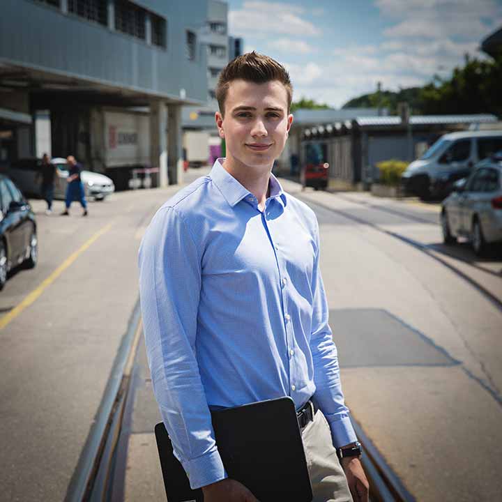 Ein Praktikant im Bereich Logistik vor einem Gebäude der BMW Group.