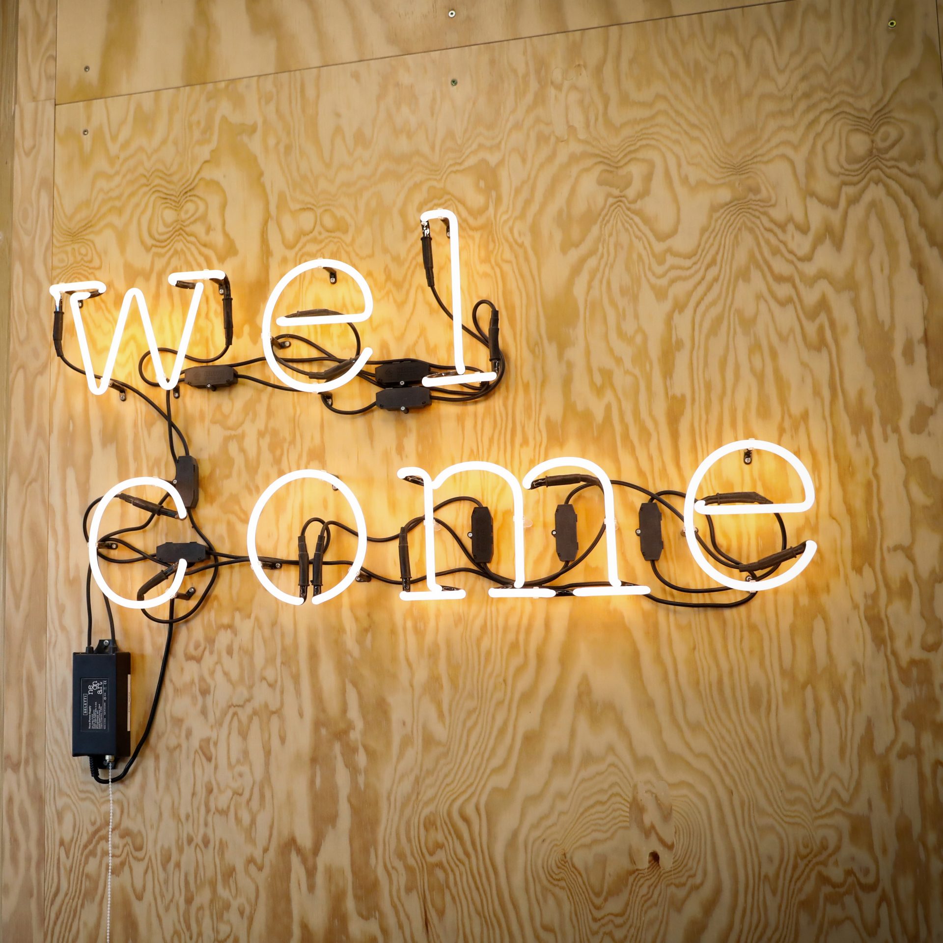 Neonzeichen mit dem Wort 'welcome' an einer Holzwand bei BMW