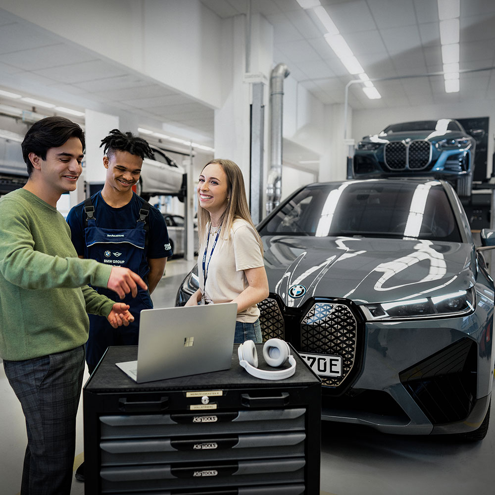 Three BMW Employees working on a BMW iX with a laptop in a service environment.