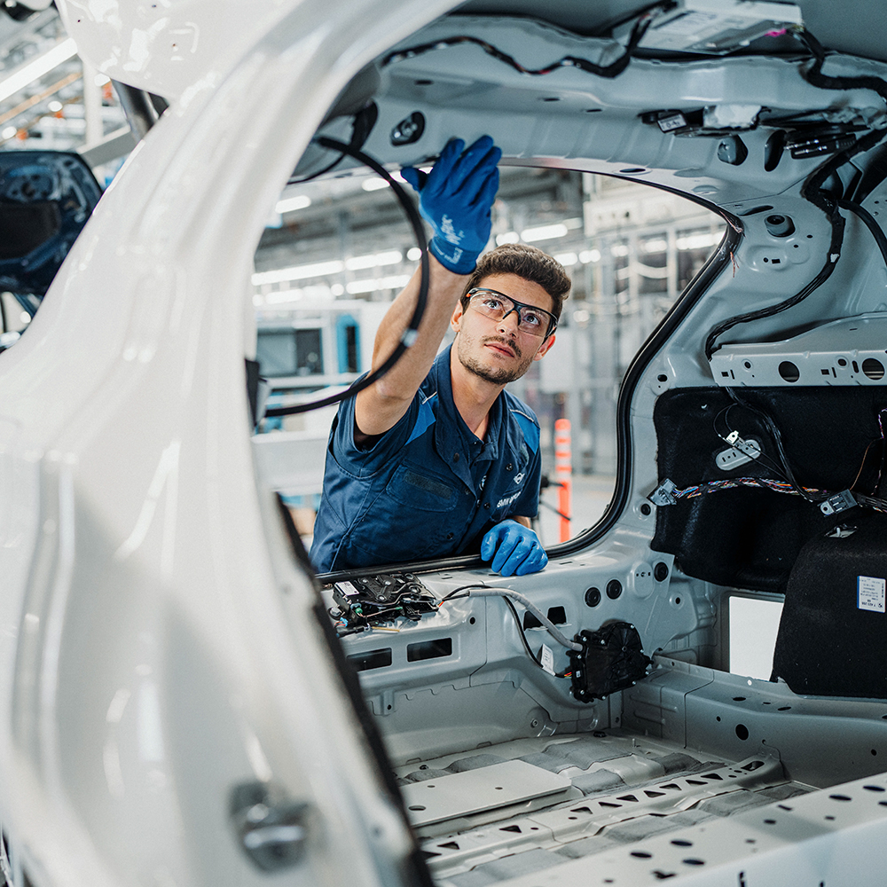 BMW Employee inspecting car chassis at BMW production facility.