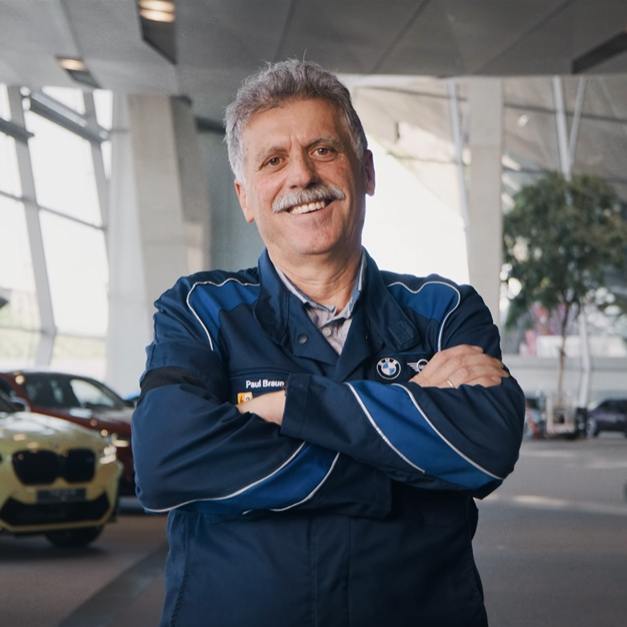 Engineer Paul standing in the BMW Welt Munich (smiling)