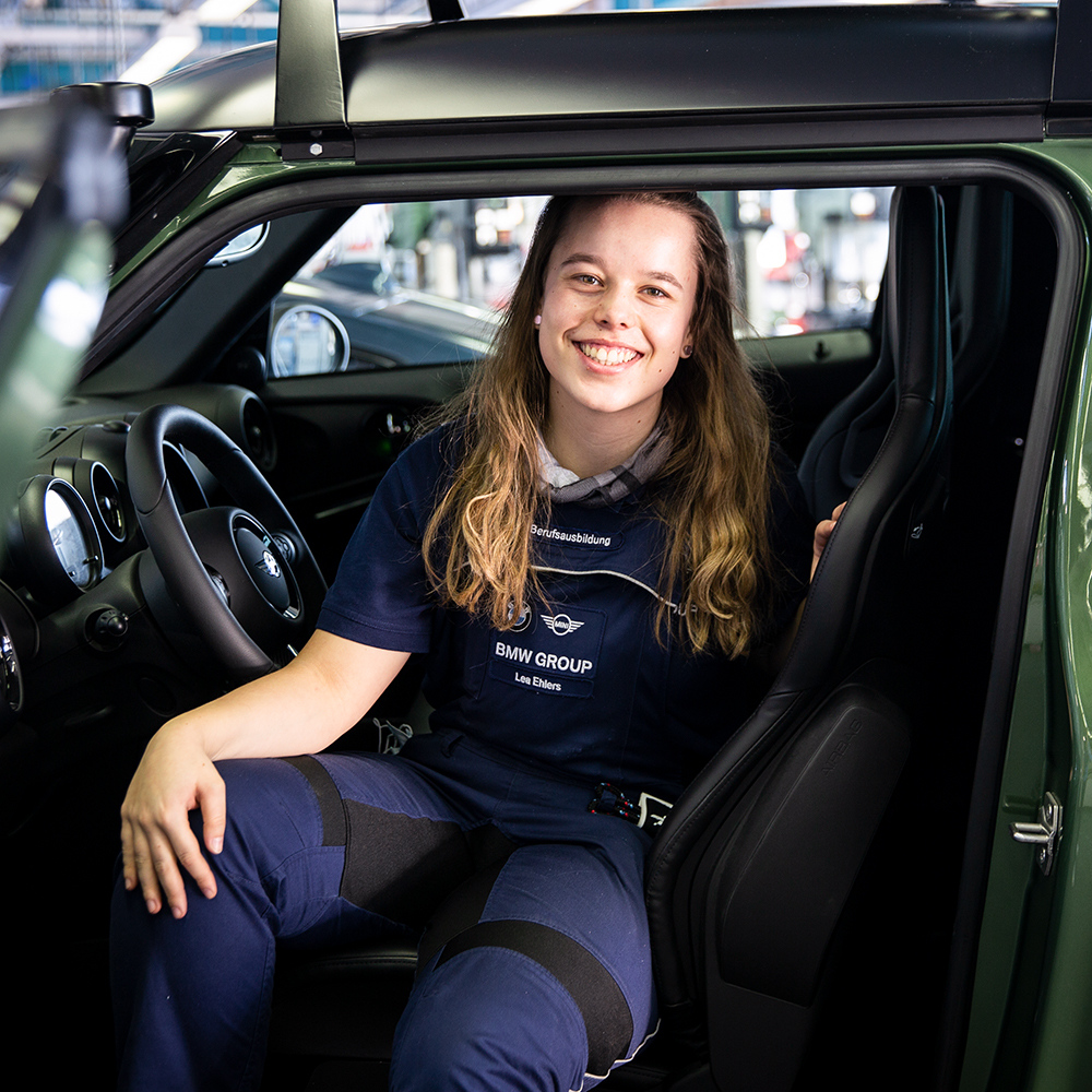 BMW apprentice in bodywork and vehicle technology smiling inside a MINI.