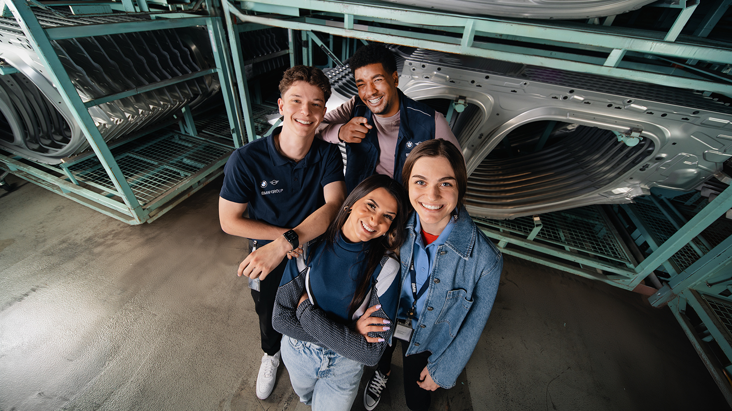 Four laughing apprentices in the car body warehouse