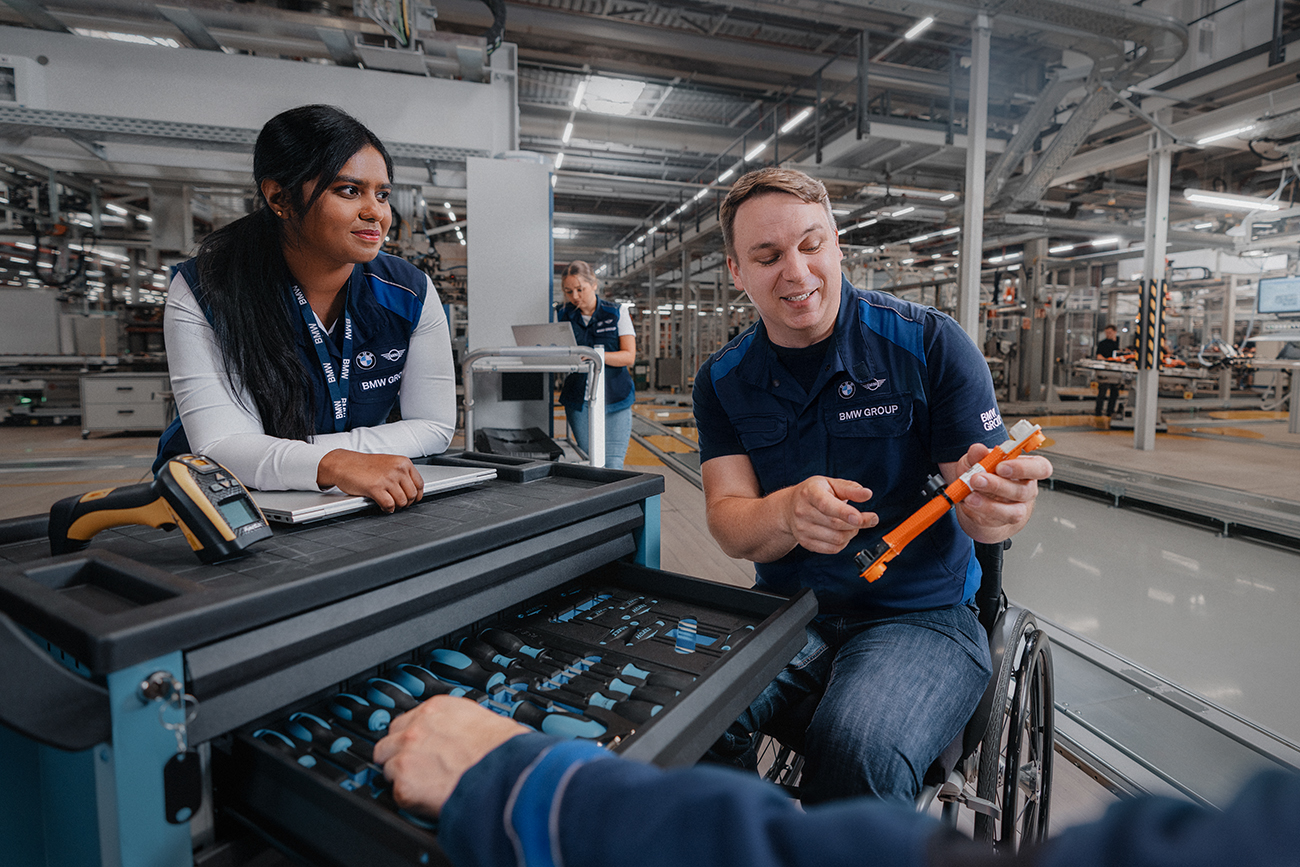 Two colleagues, one in a wheelchair, working in production.  