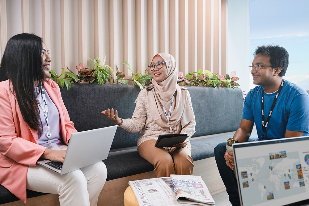Three employees from various cultural backgrounds having a chat in the office