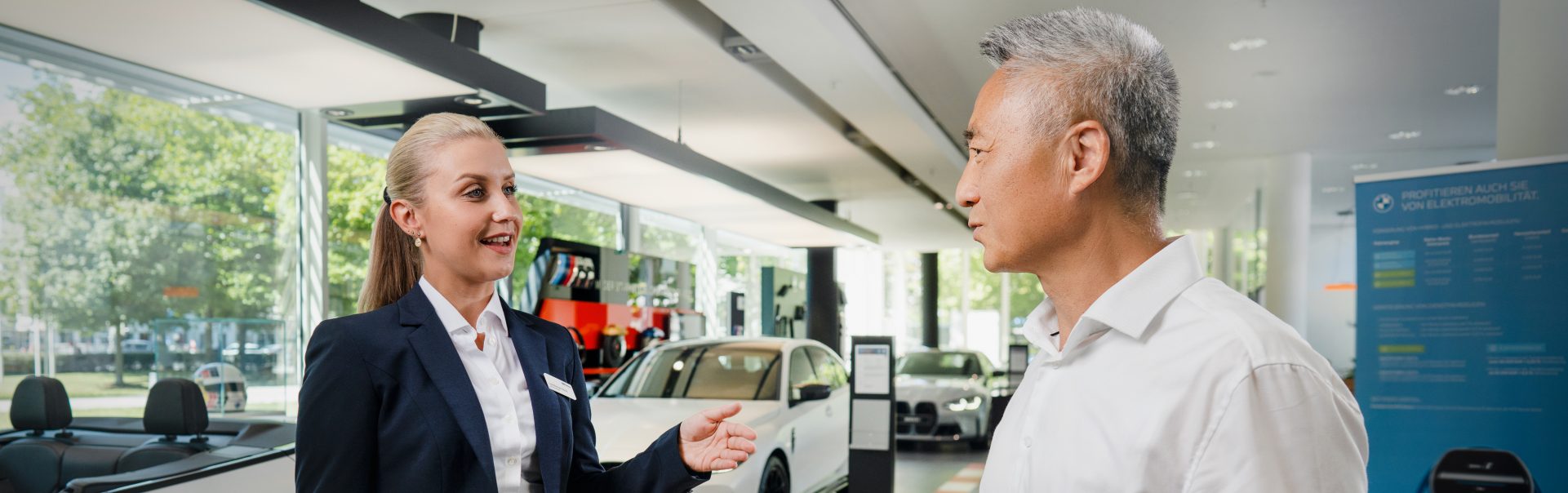 A professional interaction between a car sales representative and a customer in a BMW dealership.