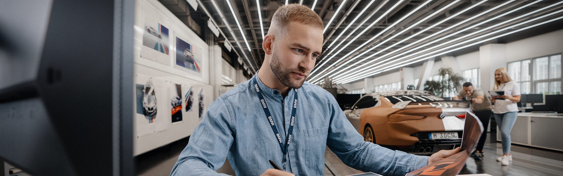 An automotive designer sketching a new car concept in a contemporary design studio.