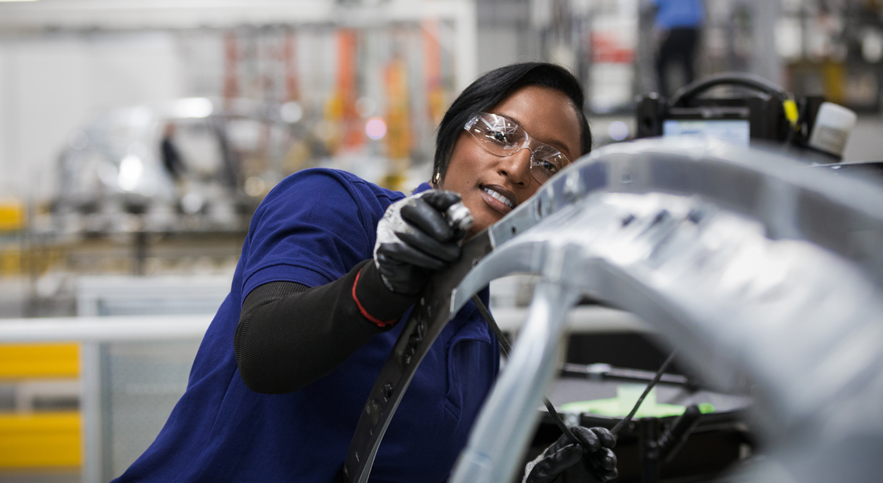 A young woman working on a BMW car body.