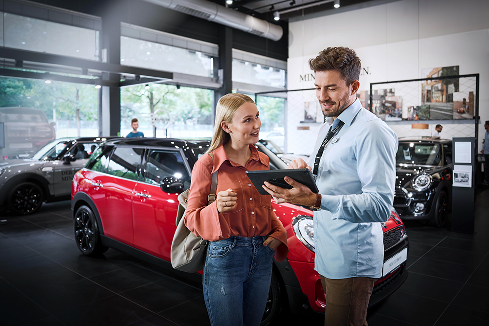 A kind salesperson in a BMW car dealership having a conversation with a customer.