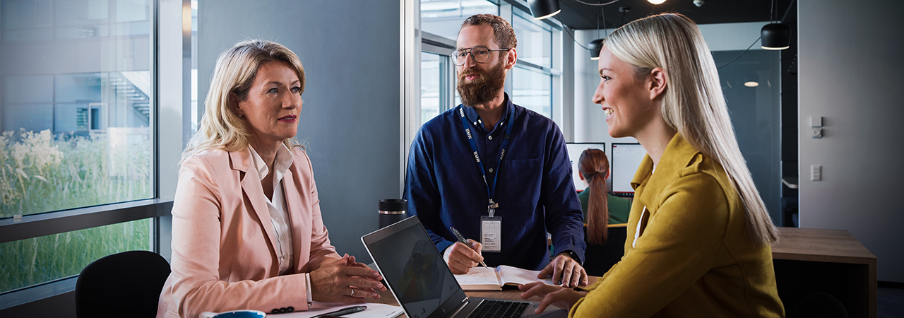 Three BMW professionals, two women and a man, are attending a meeting.