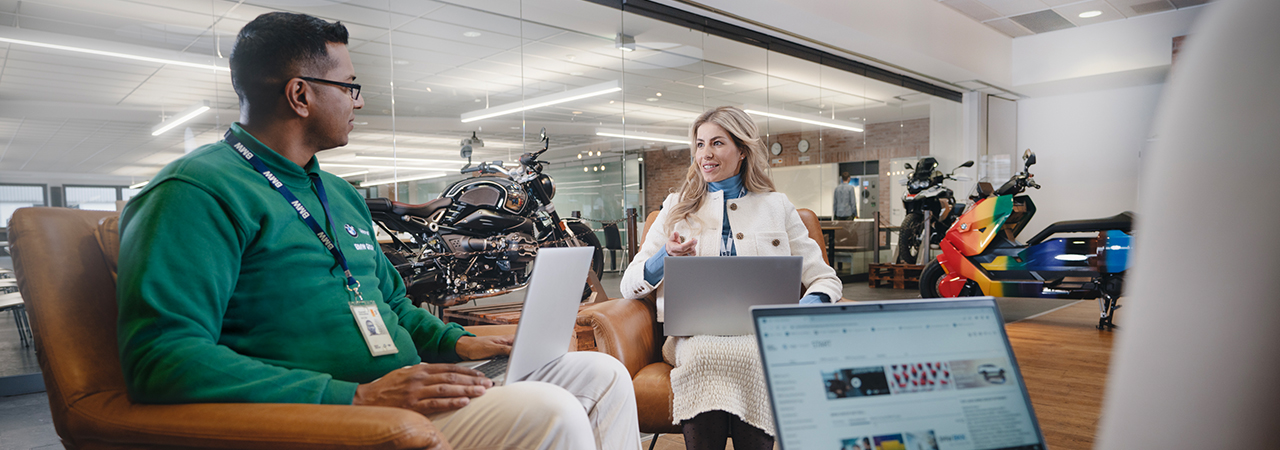 Two BMW employees are working together on a laptop and laughing.