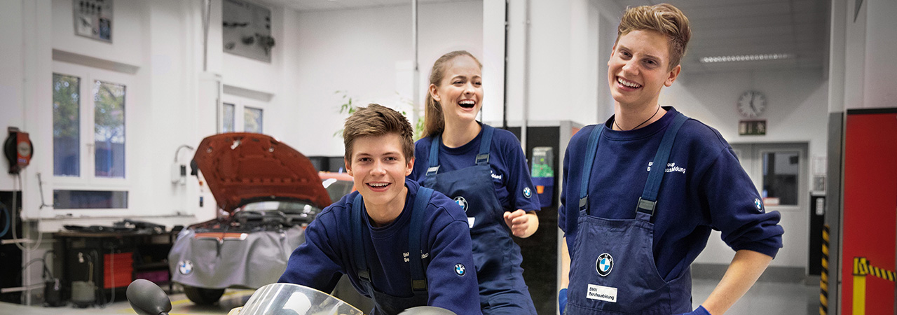 The photo shows three apprentices in a BMW work shop.
