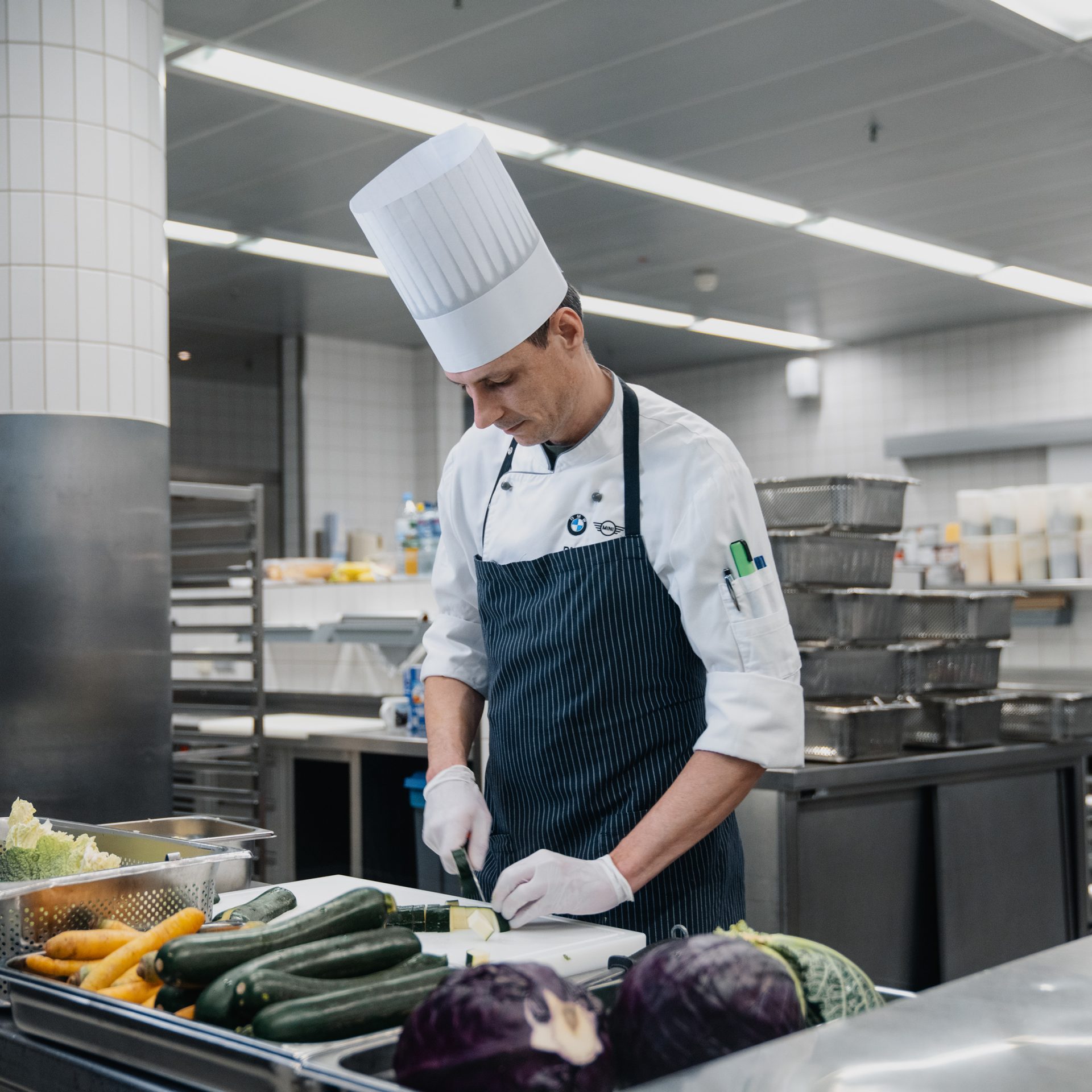 The image shows two BMW employees working in the kitchen.