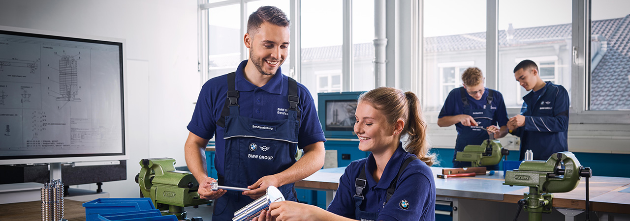 The picture shows two students working very precisely during their internship at BMW.