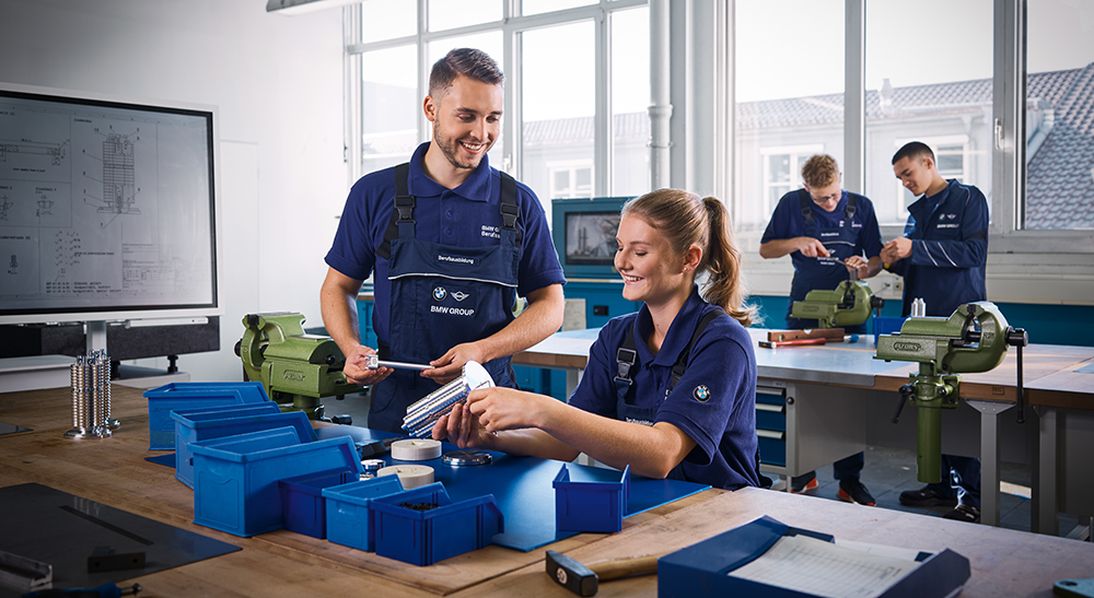 The picture shows two students working very precisely during their internship at BMW.