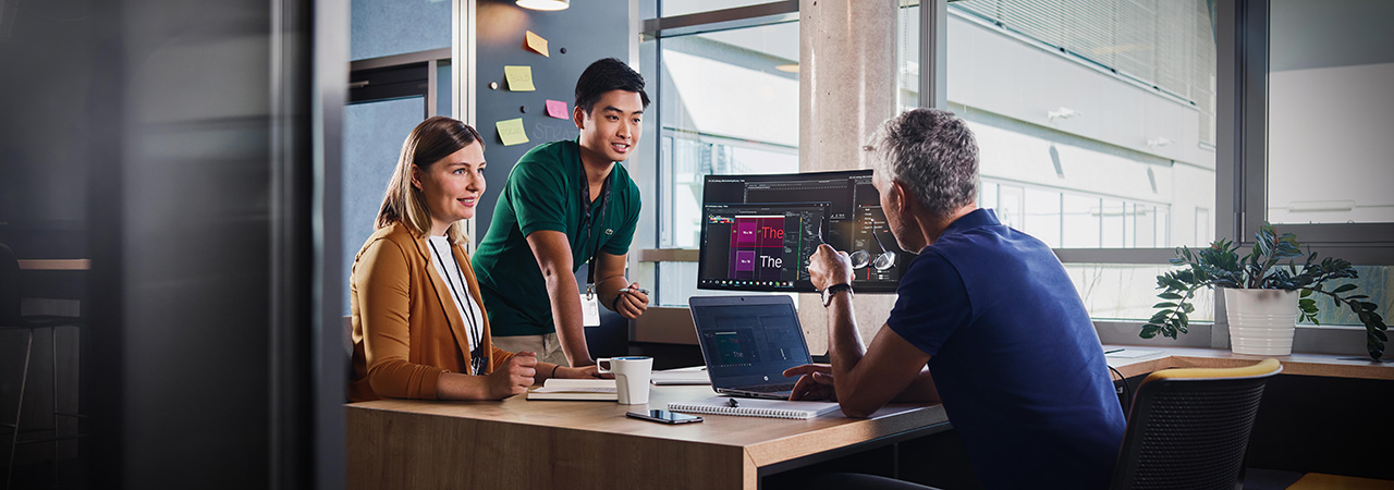 Two students talking with a BMW employee in a modern office environment.
