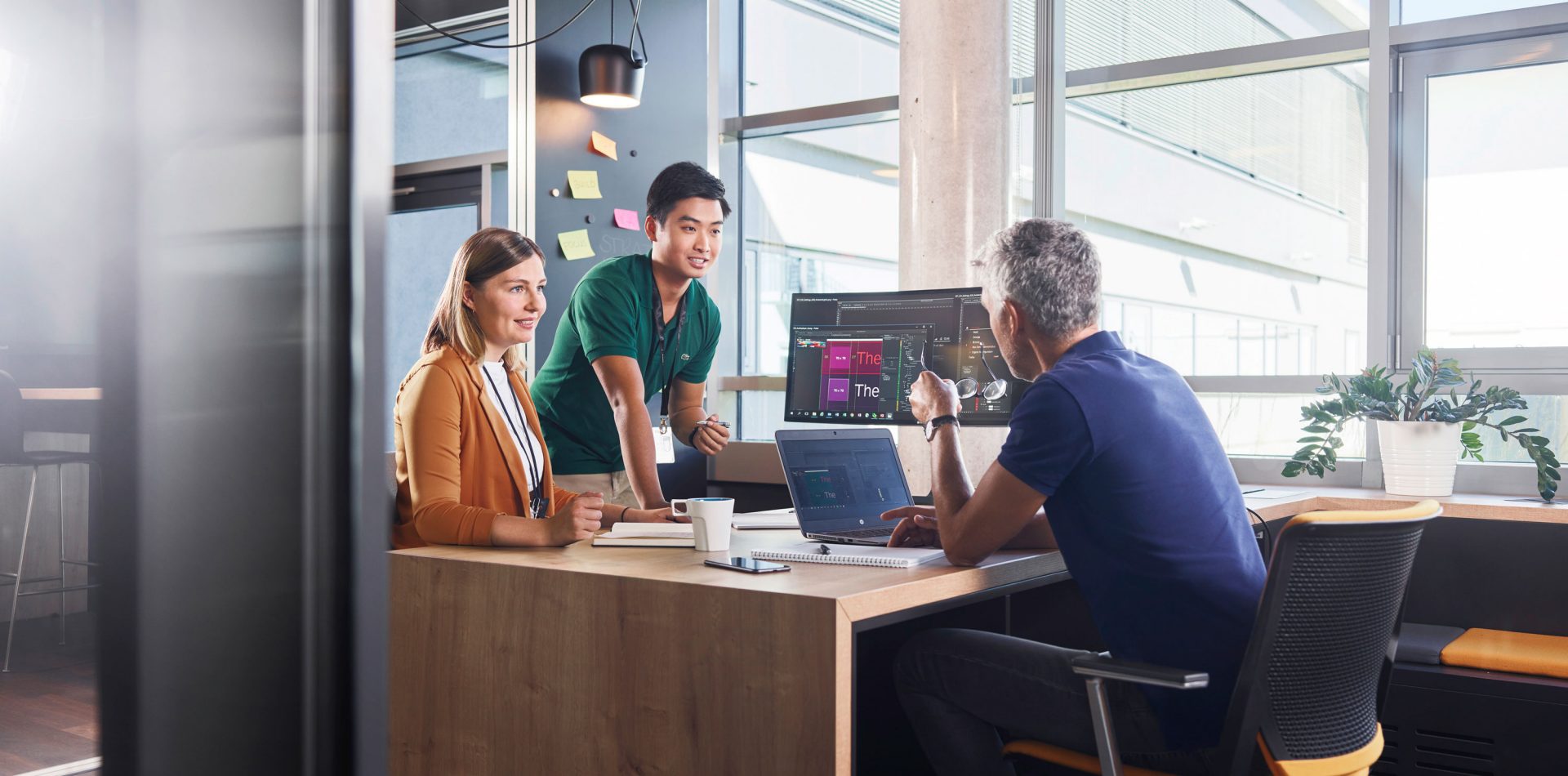 Two Students and a BMW employee are having a collaborative conversation in a modern office setting.