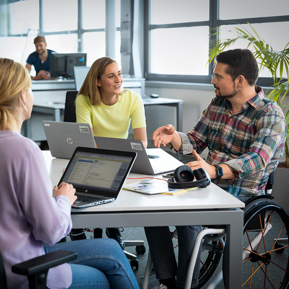 A group of colleagues, one in a wheelchair, are having a meeting.