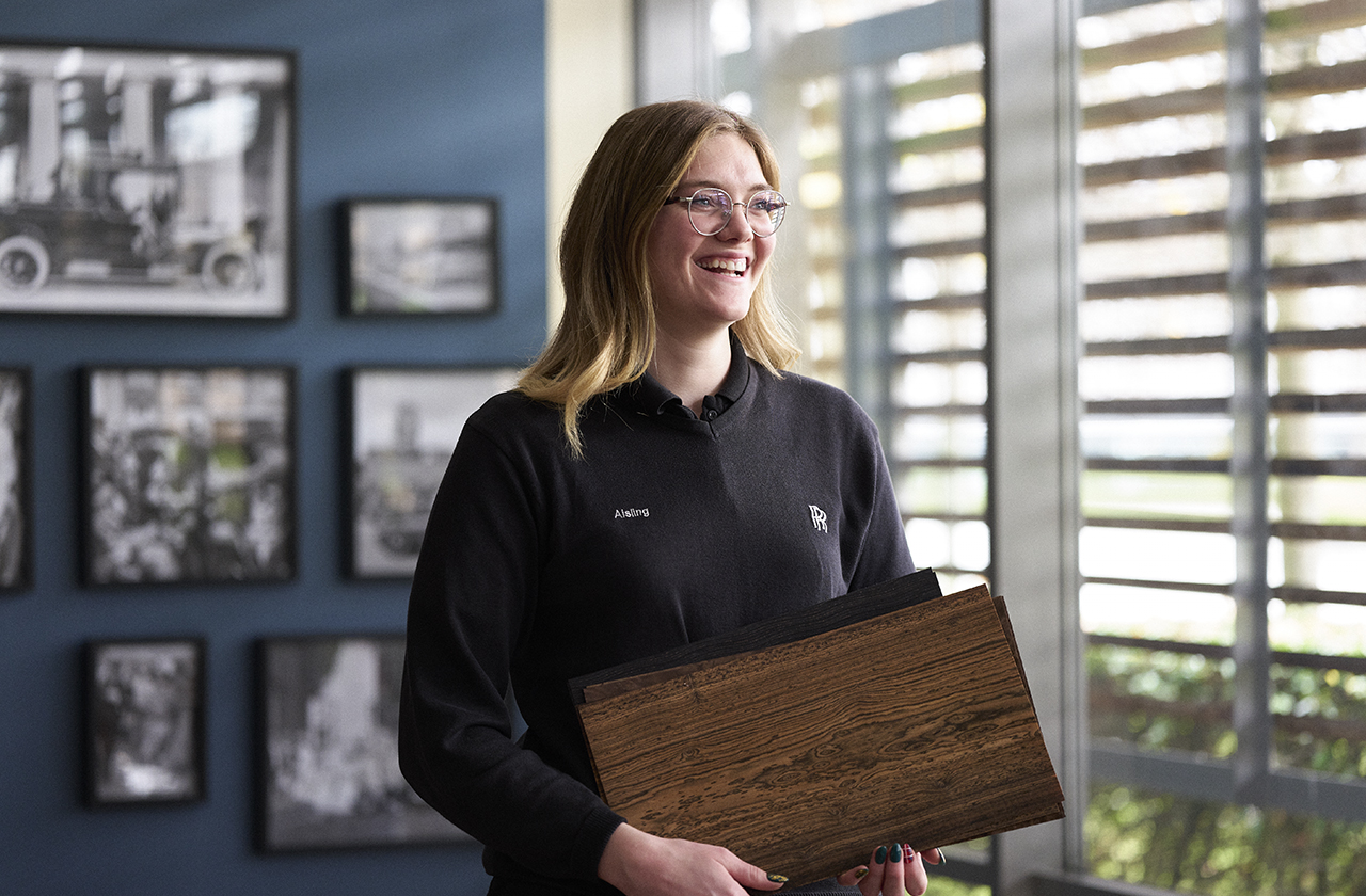 Apprentice Aisling smilling at while holding wood trim