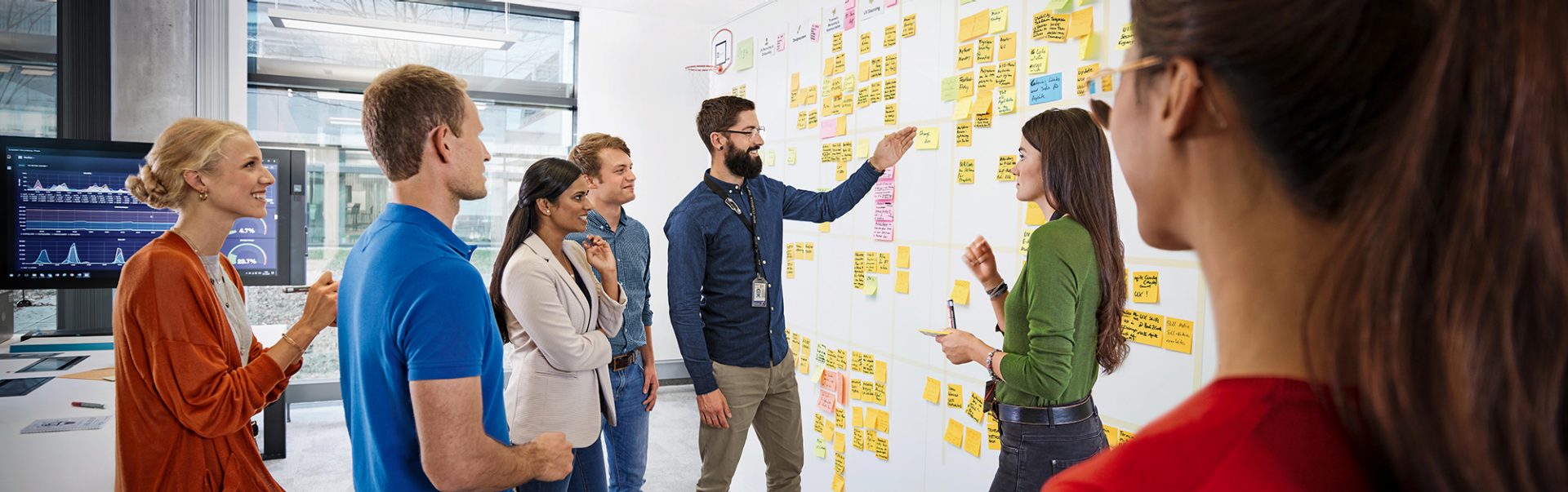 The image shows a stand-up meeting of a team at the BMW Group.