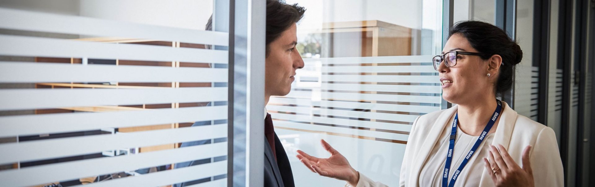 The image shows two BMW Group colleagues talking.