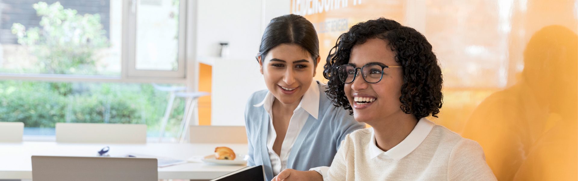 The image shows two women laughing.